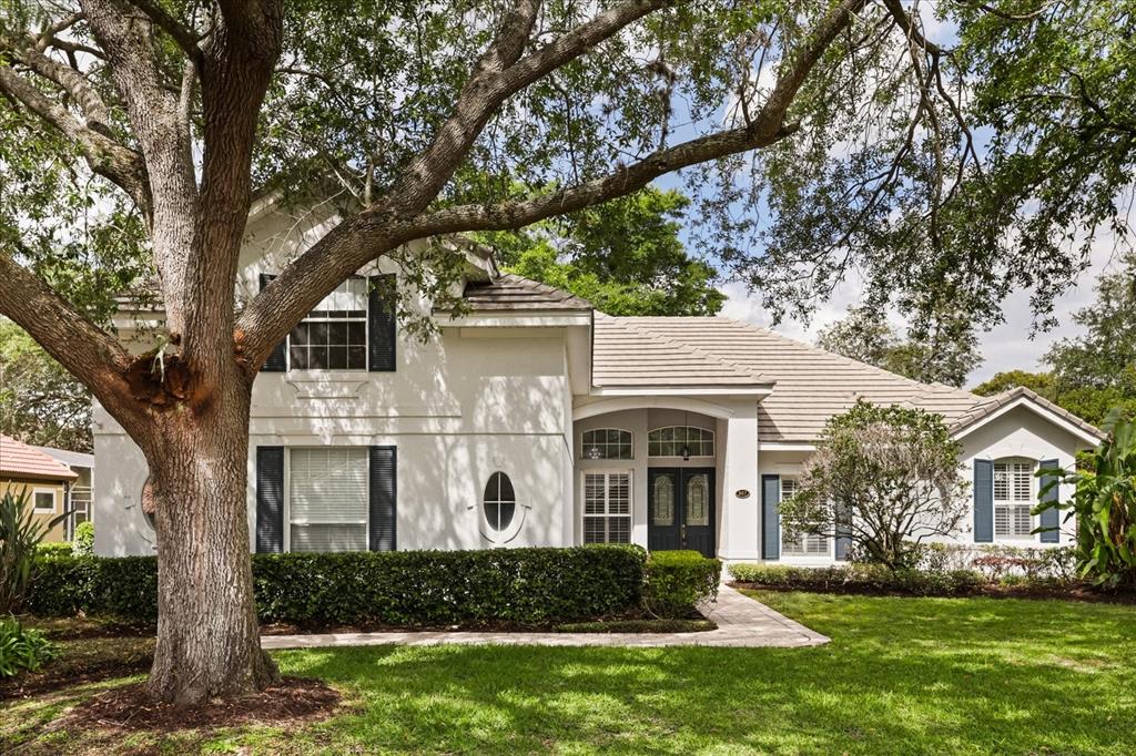 A two-story house with white stucco siding, dark shutters, and a large tree in front — 987 BRIGHTWATER CIRCLE, MAITLAND, FL