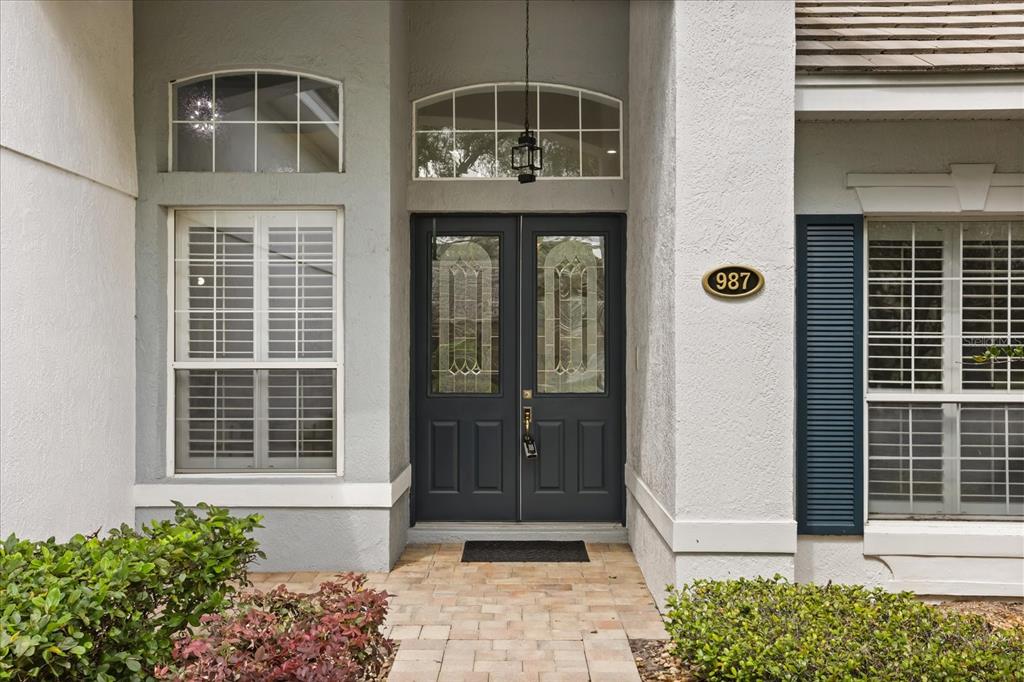 The front entrance features a dark double door with glass panels and a house number plaque — 987 BRIGHTWATER CIRCLE, MAITLAND, FL