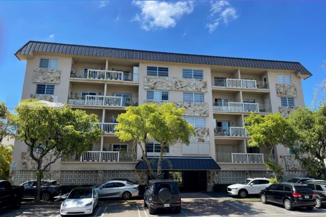 A multi-story apartment building with balconies and a parking lot in the foreground — BAY HARBOR ISLANDS, FL