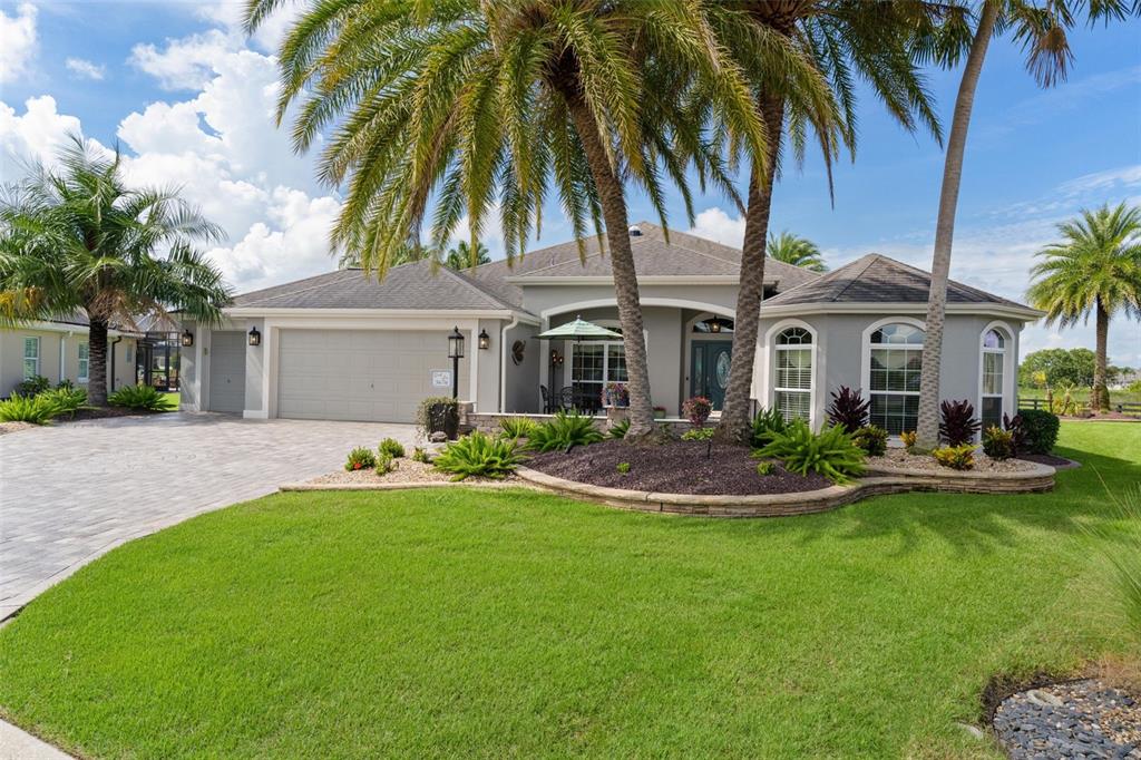 A single-story house with a gray exterior, a paved driveway, and palm trees in front — 3676 VINELAND AVENUE, THE VILLAGES, FL