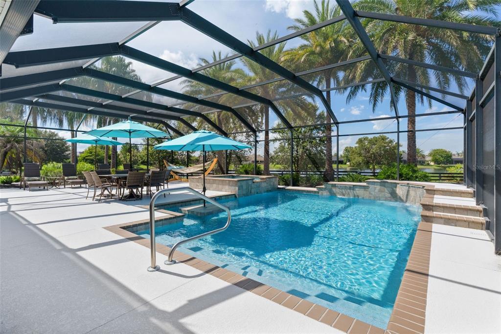 A screened-in patio features a swimming pool with a hot tub and outdoor dining furniture — 3676 VINELAND AVENUE, THE VILLAGES, FL
