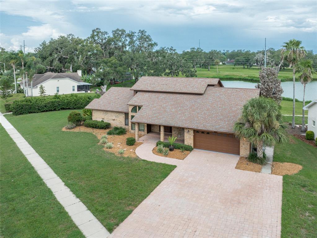 An aerial view shows a single-story brick house with a brown roof and paved driveway — 6151 SILVER OAKS DRIVE, ZEPHYRHILLS, FL