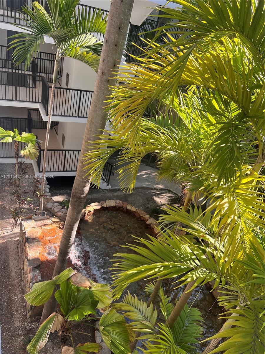 A view from above shows a small stone-lined pond surrounded by palm trees and balconies — 55 Ocean Lane Dr # 3030, Key Biscayne FL 33149, KEY BISCAYNE, FL