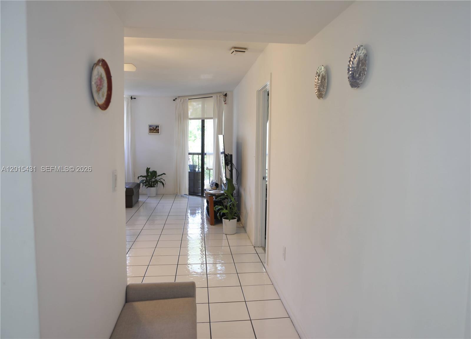 A hallway with white tile floors leads into a living area with a balcony door — 55 Ocean Lane Dr # 3030, Key Biscayne FL 33149, KEY BISCAYNE, FL