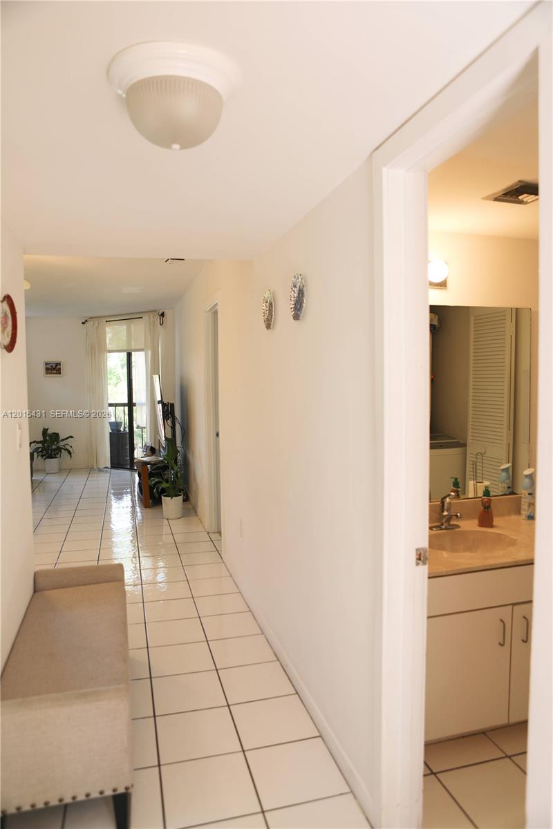 A hallway with white tile floors leads to a living area, with a bathroom visible — 55 Ocean Lane Dr # 3030, Key Biscayne FL 33149, KEY BISCAYNE, FL