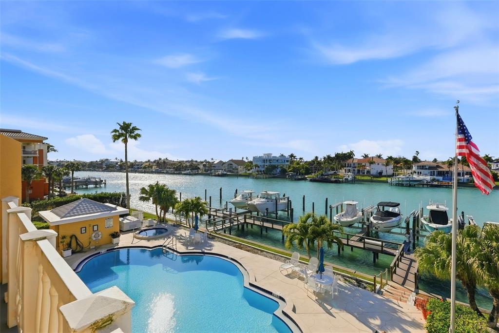 An elevated view of a swimming pool, boat docks, and a canal with residential homes — 544 PINELLAS BAYWAY S UNIT TH13, TIERRA VERDE, FL