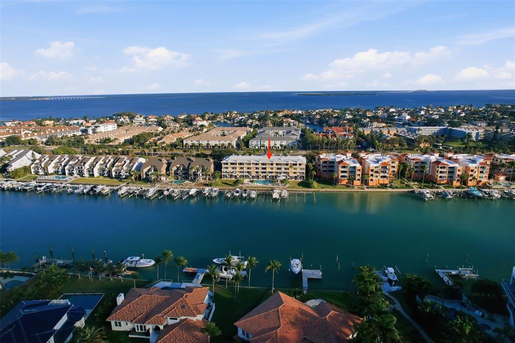 An aerial view shows a waterfront condominium building with a red arrow pointing toward it — 544 PINELLAS BAYWAY S UNIT TH13, TIERRA VERDE, FL