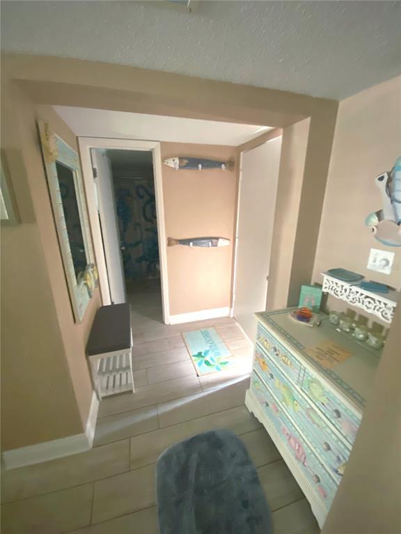 A hallway with tile flooring, a painted dresser, a bench, and coastal-themed wall decor — 4175 S ATLANTIC AVENUE UNIT 3160, NEW SMYRNA BEACH, FL