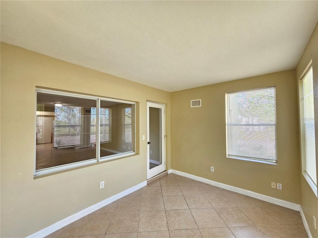A sunroom with beige walls, tile flooring, a glass door, and large windows — 1365 DREW STREET UNIT 102, CLEARWATER, FL