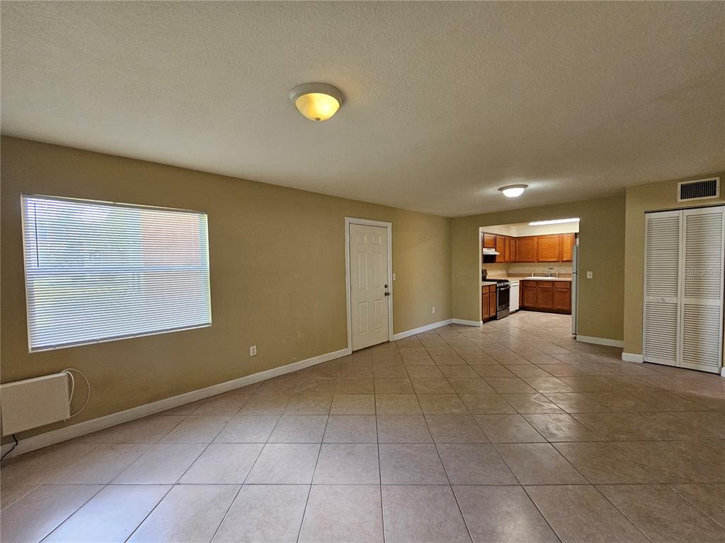 An open-concept living area with tile flooring leads into a kitchen with wood cabinets — 1365 DREW STREET UNIT 102, CLEARWATER, FL