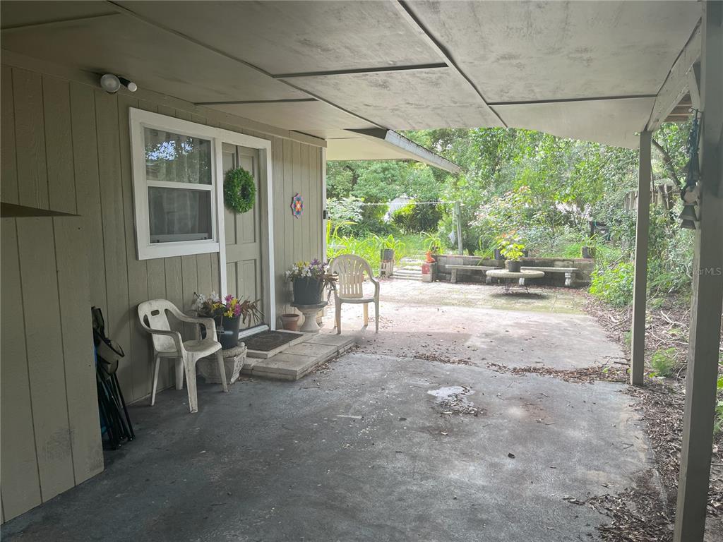 A covered concrete patio features a door, a window, and outdoor seating — 1874 DOUGLAS AVENUE, CLEARWATER, FL