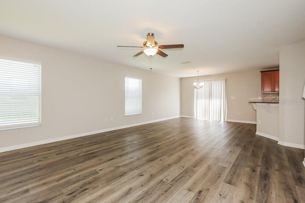 An open living area features light-colored walls, wood-look flooring, a ceiling fan, and sliding doors — 9540 SIMEON DRIVE, LAND O LAKES, FL