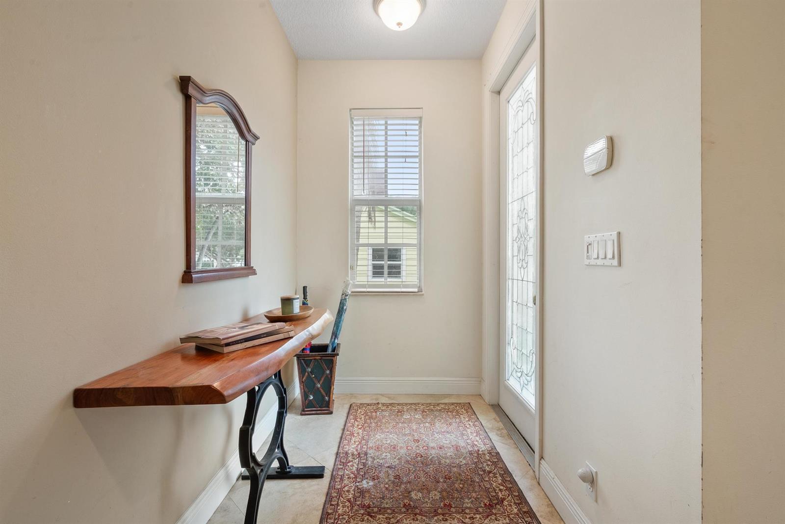 An entryway features a live-edge console table, a decorative mirror, and a patterned area rug — 218 N Palmway, FL 33460, FL