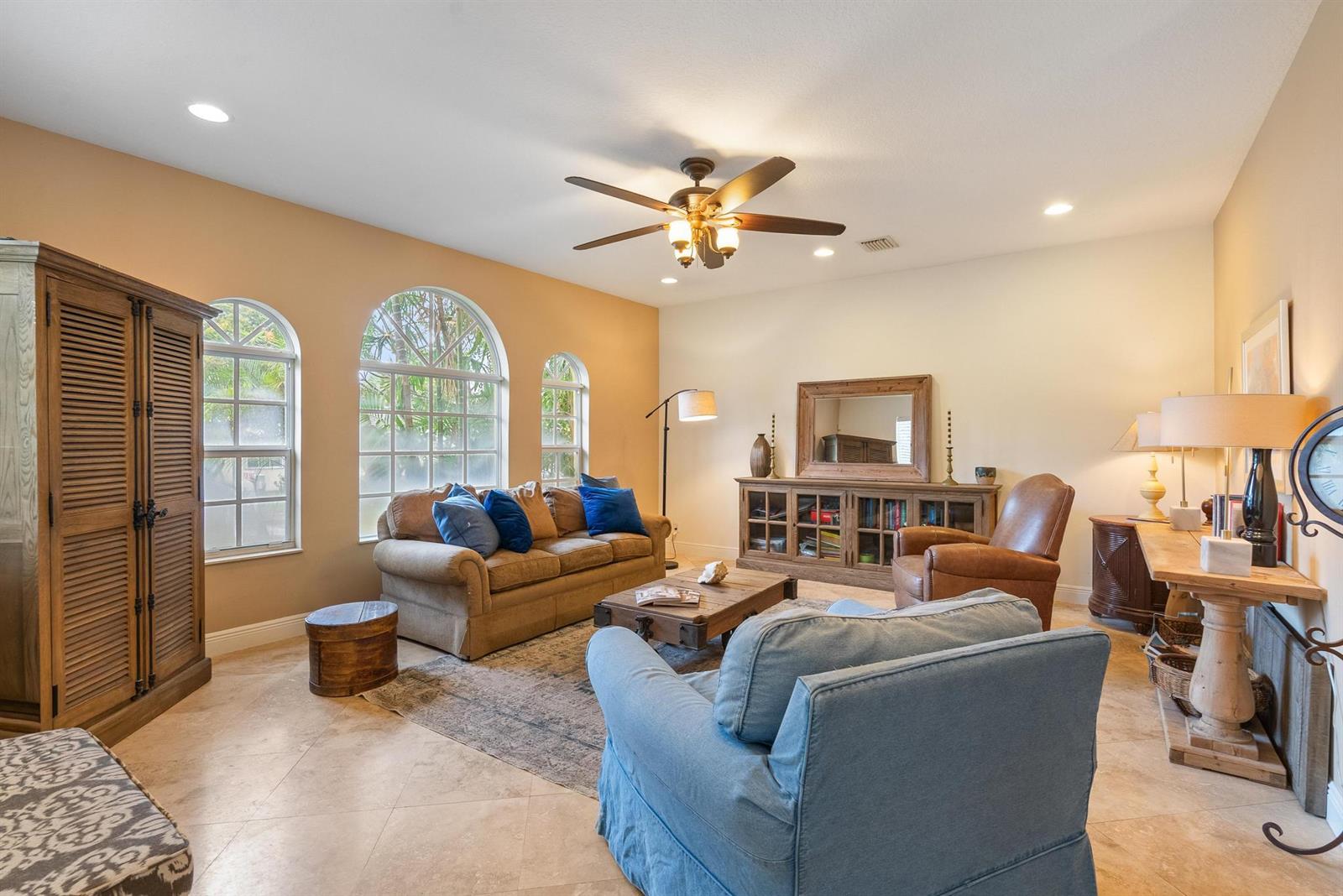 A living room features arched windows, tile flooring, a ceiling fan, and traditional wood furniture — 218 N Palmway, FL 33460, FL