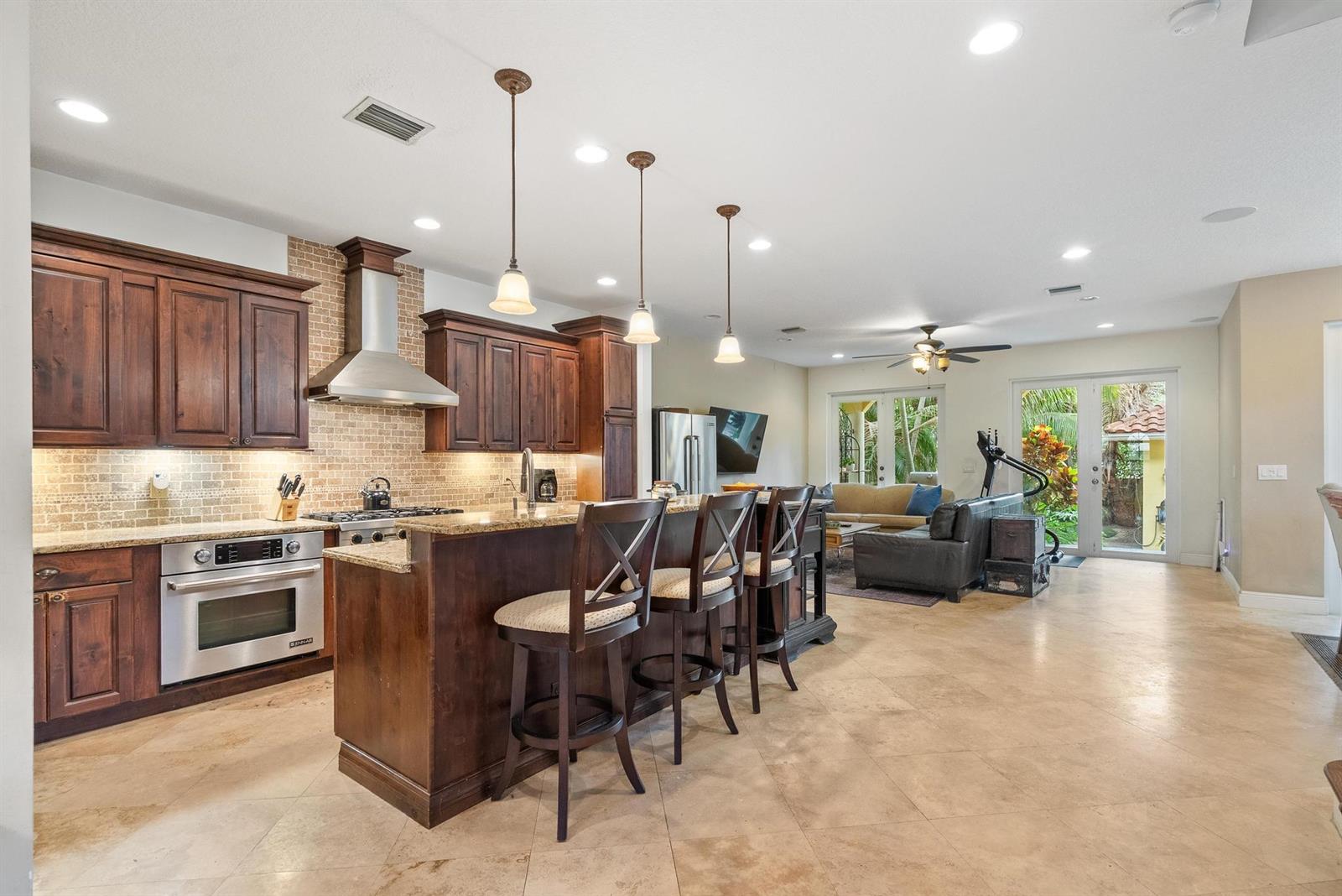 A kitchen with dark wood cabinets and a breakfast bar opens into a living area — 218 N Palmway, FL 33460, FL