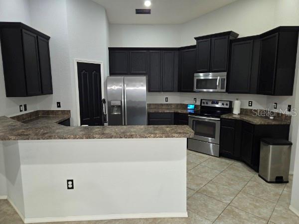 A kitchen features dark cabinets, stainless steel appliances, and a breakfast bar with laminate countertops — 2235 LAKERIDGE DRIVE, WINTER HAVEN, FL