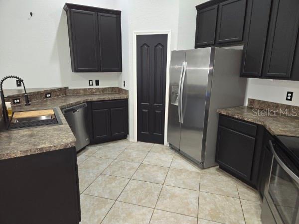 A kitchen features dark cabinets, brown laminate countertops, stainless steel appliances, and tiled flooring — 2235 LAKERIDGE DRIVE, WINTER HAVEN, FL