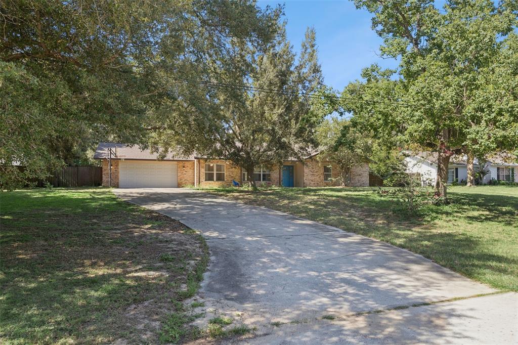 A single-story brick house with a two-car garage and a concrete driveway sits among trees — 16045 HARBAR OAKS DRIVE, MONTVERDE, FL
