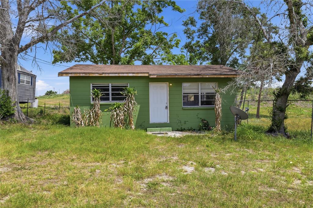 A small, green, single-story house with a white door sits on a grassy lot — 4610 WEEPING WILLOW AVENUE, SEBRING, FL