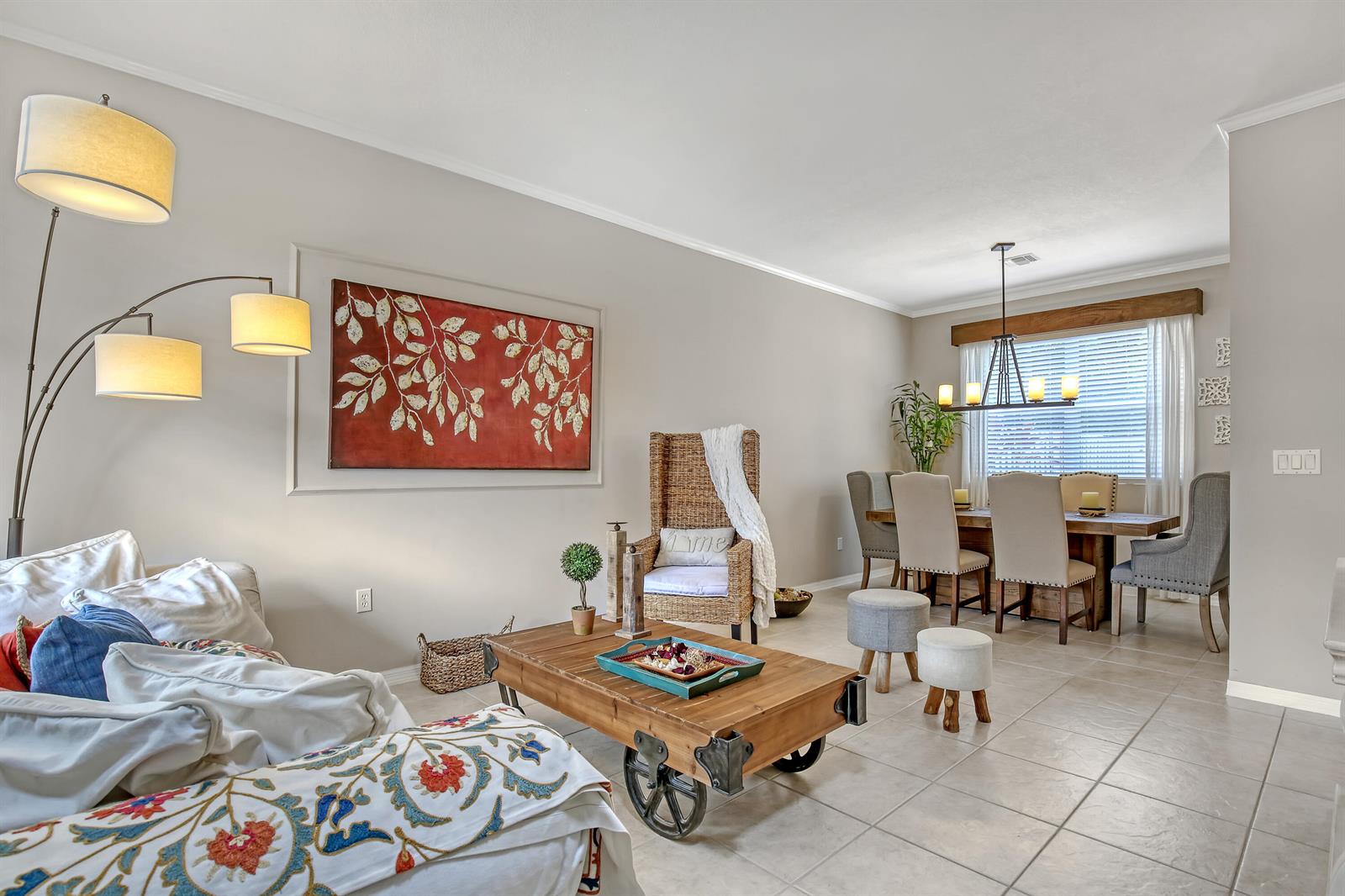 A living and dining area features a wooden cart coffee table, wicker chair, and tile flooring — 10751 Oak Bend Way, Wellington FL 33414, WELLINGTON, FL