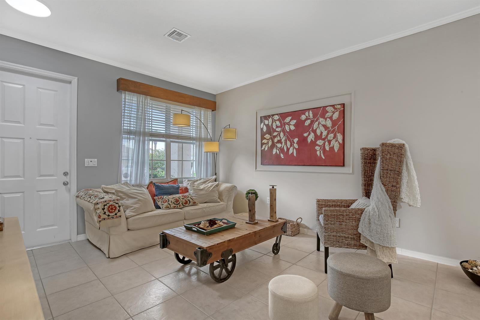 A living room features a beige sofa, a wooden cart coffee table, and a wicker chair — 10751 Oak Bend Way, Wellington FL 33414, WELLINGTON, FL