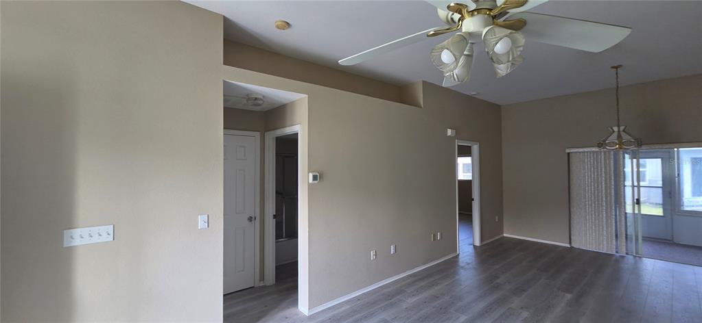 A living area features light-colored walls, wood-look flooring, a ceiling fan, and sliding glass doors — 4224 AVANTI CIRCLE, NEW PORT RICHEY, FL