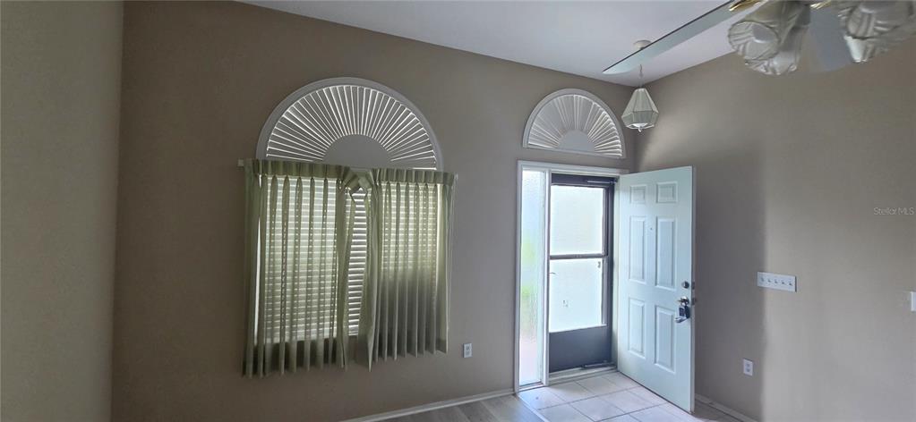 An entryway features a light-colored door, arched windows with blinds, and a ceiling fan — 4224 AVANTI CIRCLE, NEW PORT RICHEY, FL