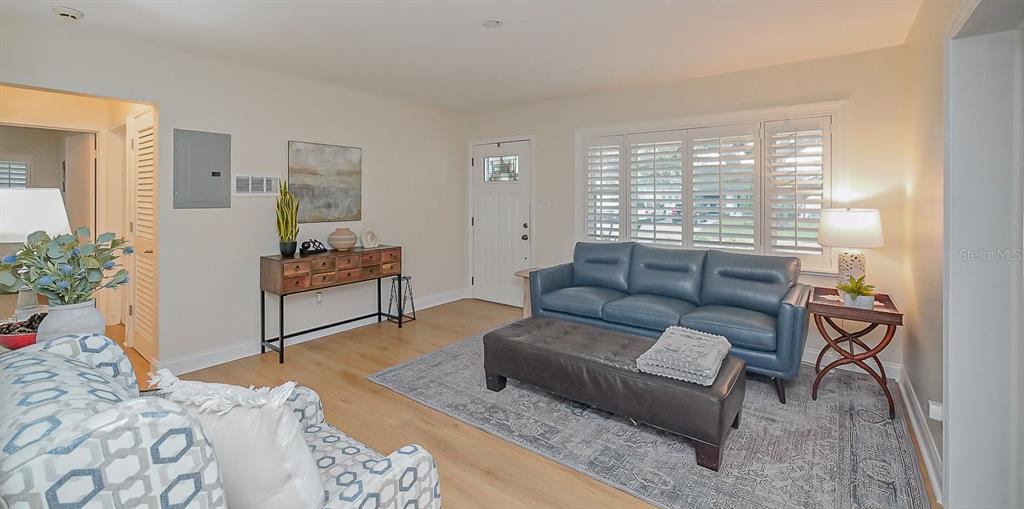 A living room features a blue sofa, a dark ottoman, and light wood flooring — 3207 W NASSAU STREET, TAMPA, FL