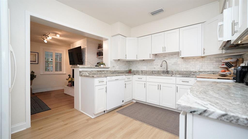 A kitchen with white cabinets, marble-patterned countertops, and a view into an adjacent living room — 3207 W NASSAU STREET, TAMPA, FL