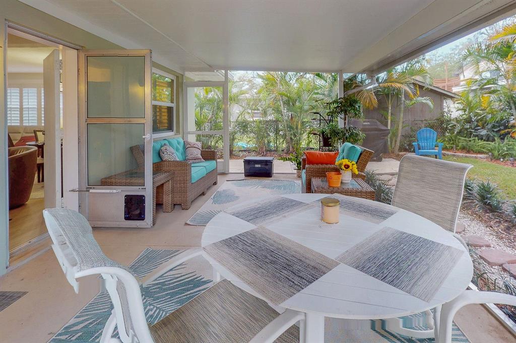 A screened-in patio features wicker furniture, a white dining table, and views of the yard — 3207 W NASSAU STREET, TAMPA, FL