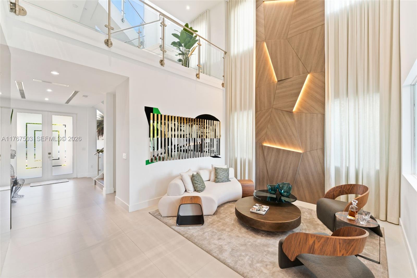 A modern living room features a double-height ceiling, wood-paneled accent wall, and curved furniture — 10561 NW 67th Ter # 10561, Doral FL 33178, DORAL, FL