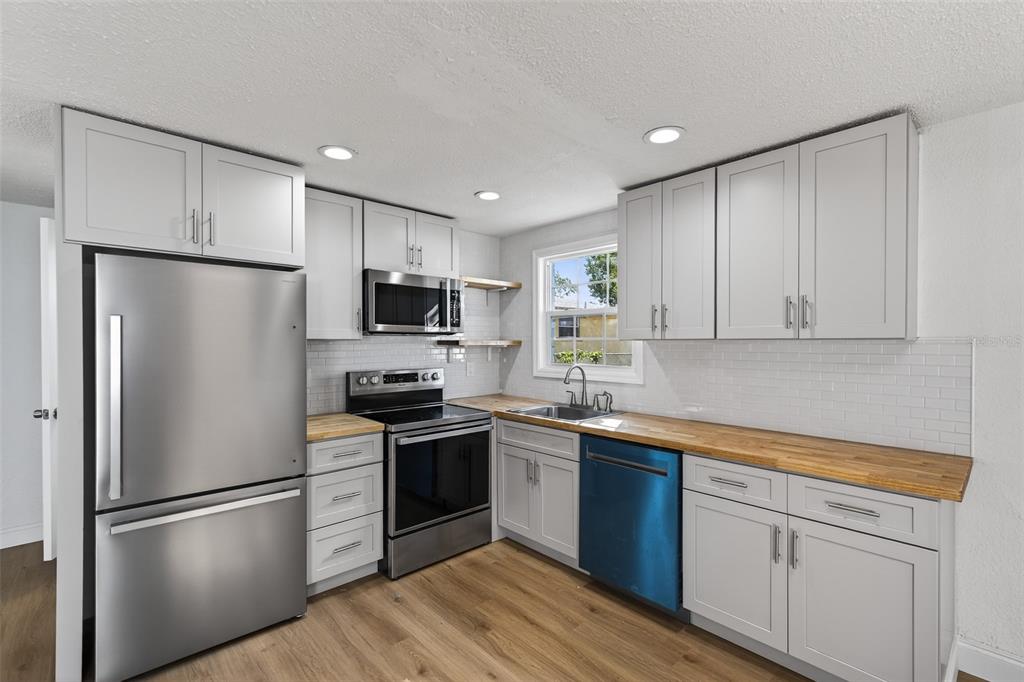 A kitchen with light gray cabinets, stainless steel appliances, wood countertops, and light wood flooring — 4545 12TH AVENUE S, ST PETERSBURG, FL