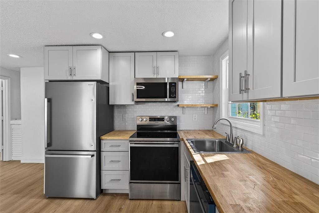 A kitchen with light gray cabinets, stainless steel appliances, and wood countertops — 4545 12TH AVENUE S, ST PETERSBURG, FL
