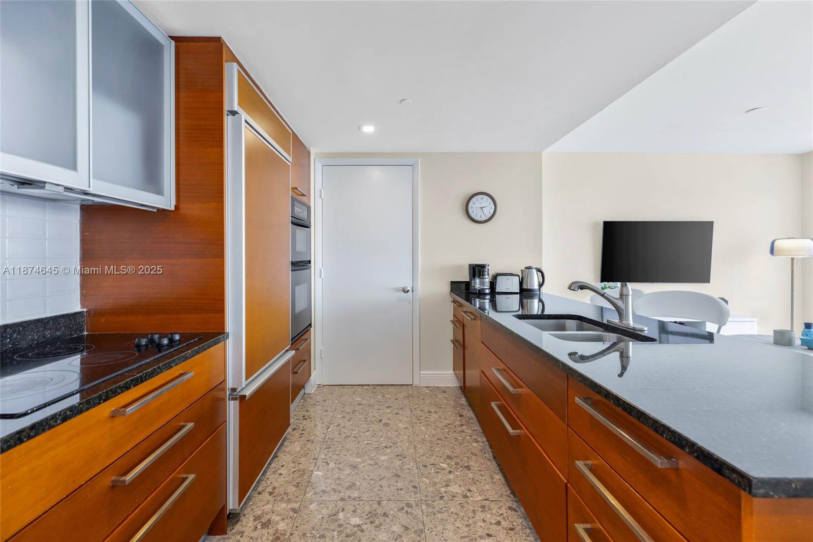 A kitchen features wood cabinetry, black countertops, stainless steel appliances, and a tiled floor — 1830 S Ocean Dr # 4107, Hallandale Beach FL 33009, HALLANDALE BEACH, FL