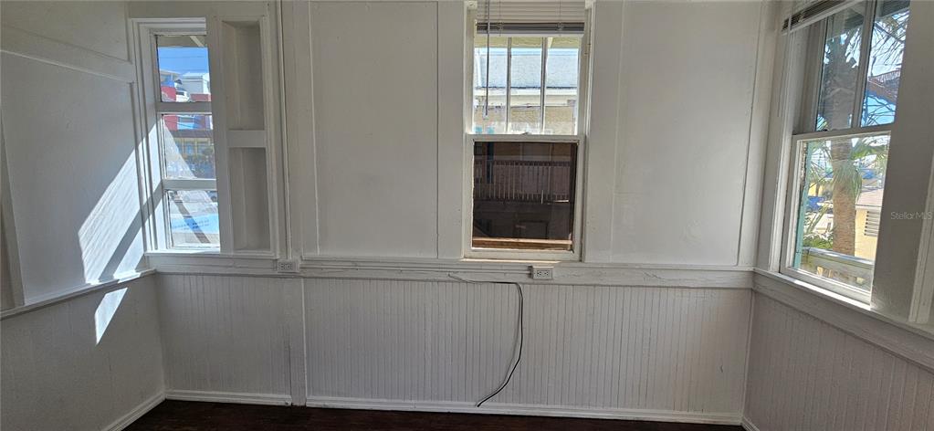 A room with white beadboard wainscoting, three windows, and an exposed electrical wire — 709 ORA STREET UNIT 06, DAYTONA BEACH, FL