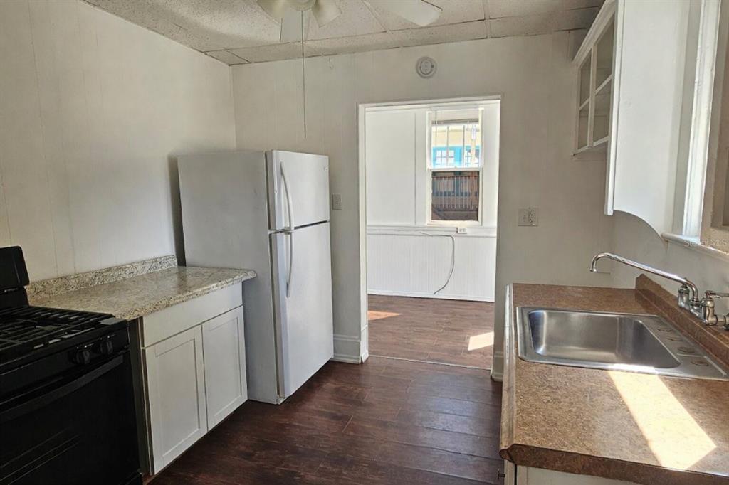 A kitchen features white cabinets, a black stove, a white refrigerator, and wood-look flooring — 709 ORA STREET UNIT 06, DAYTONA BEACH, FL