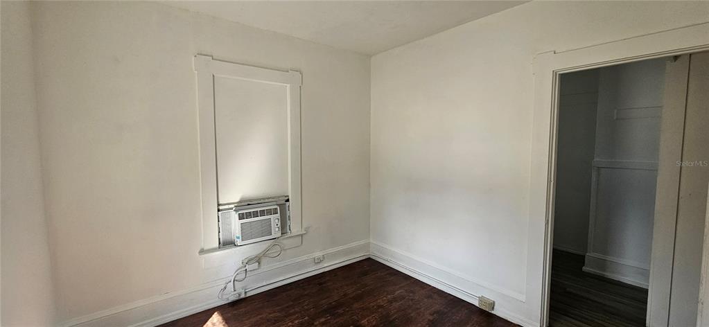 A room with white walls, dark wood flooring, and a window-mounted air conditioning unit — 709 ORA STREET UNIT 06, DAYTONA BEACH, FL