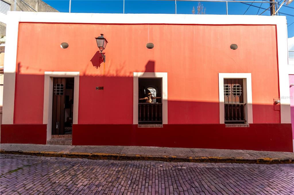 A vibrant orange building with a cobblestone street and three arched openings in the facade — 3 CRUZ, SAN JUAN, PR
