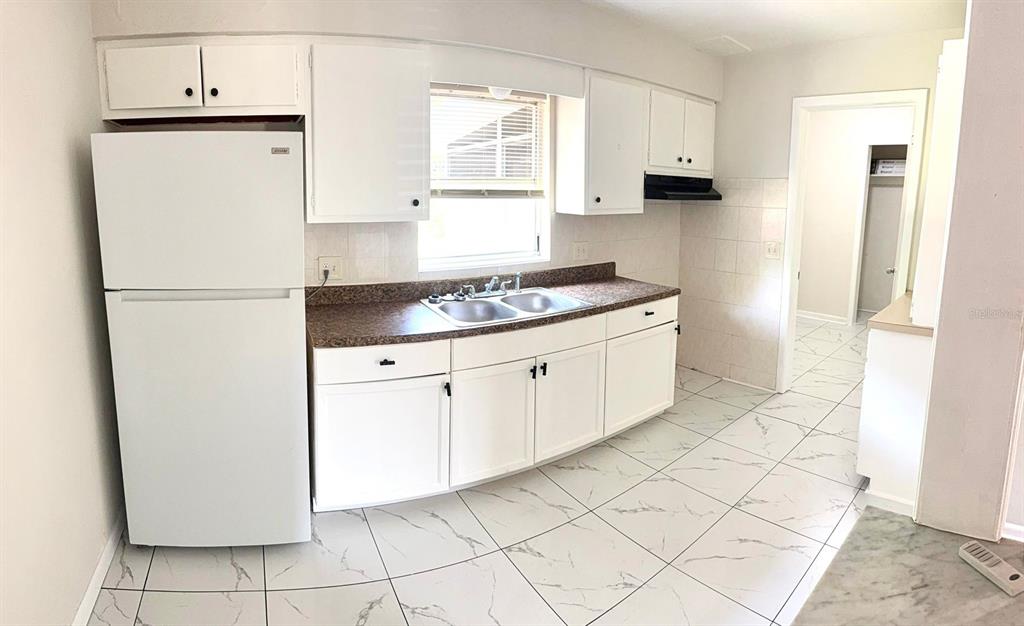 A kitchen features white cabinets, a white refrigerator, a double sink, and tiled flooring — 31 S BARBOUR STREET, BEVERLY HILLS, FL