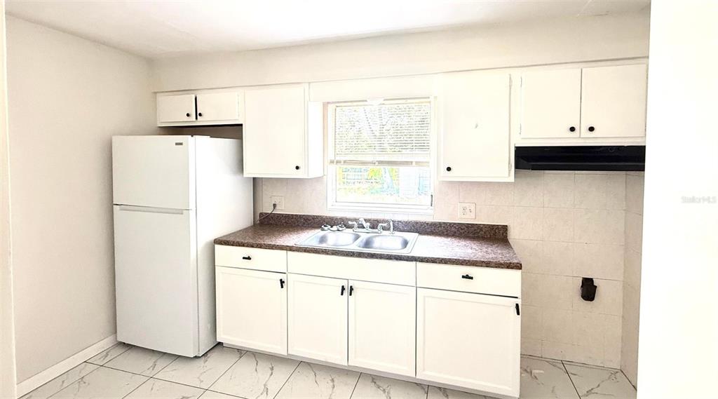 A kitchen features white cabinets, a white refrigerator, a double sink, and tiled flooring — 31 S BARBOUR STREET, BEVERLY HILLS, FL
