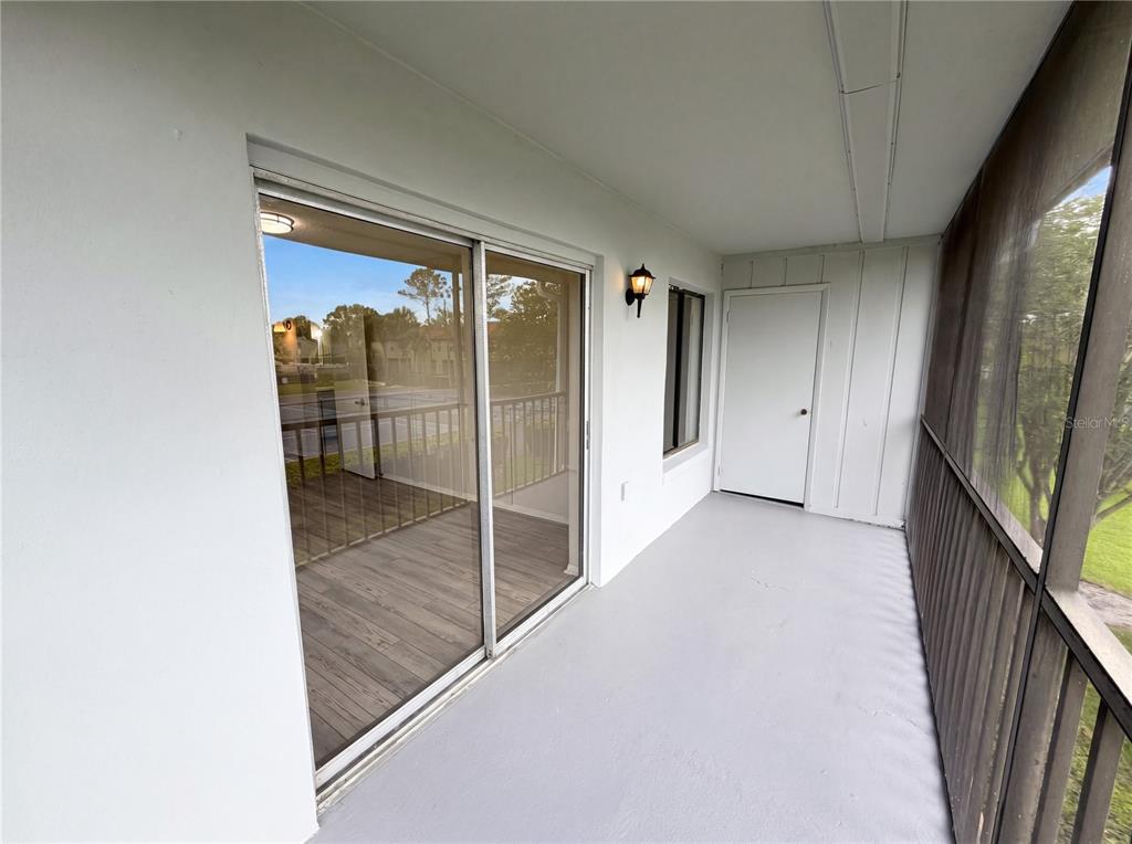 A screened-in balcony features gray painted flooring, a sliding glass door, and a storage closet — 2749 OAK PARK WAY UNIT 203, ORLANDO, FL