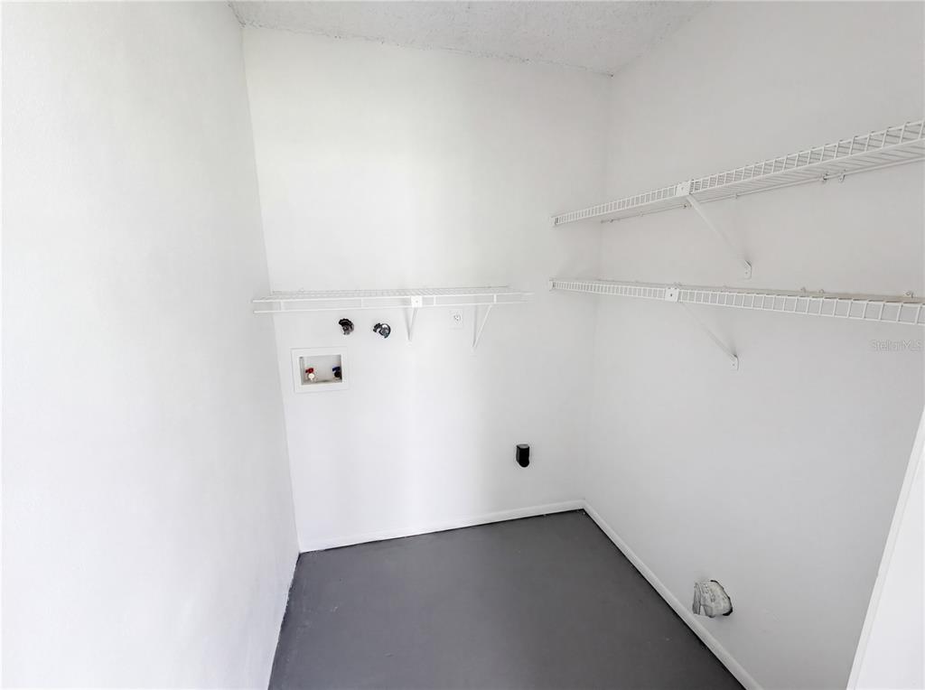 A laundry room with white walls, wire shelving, and washer and dryer hookups — 2749 OAK PARK WAY UNIT 203, ORLANDO, FL