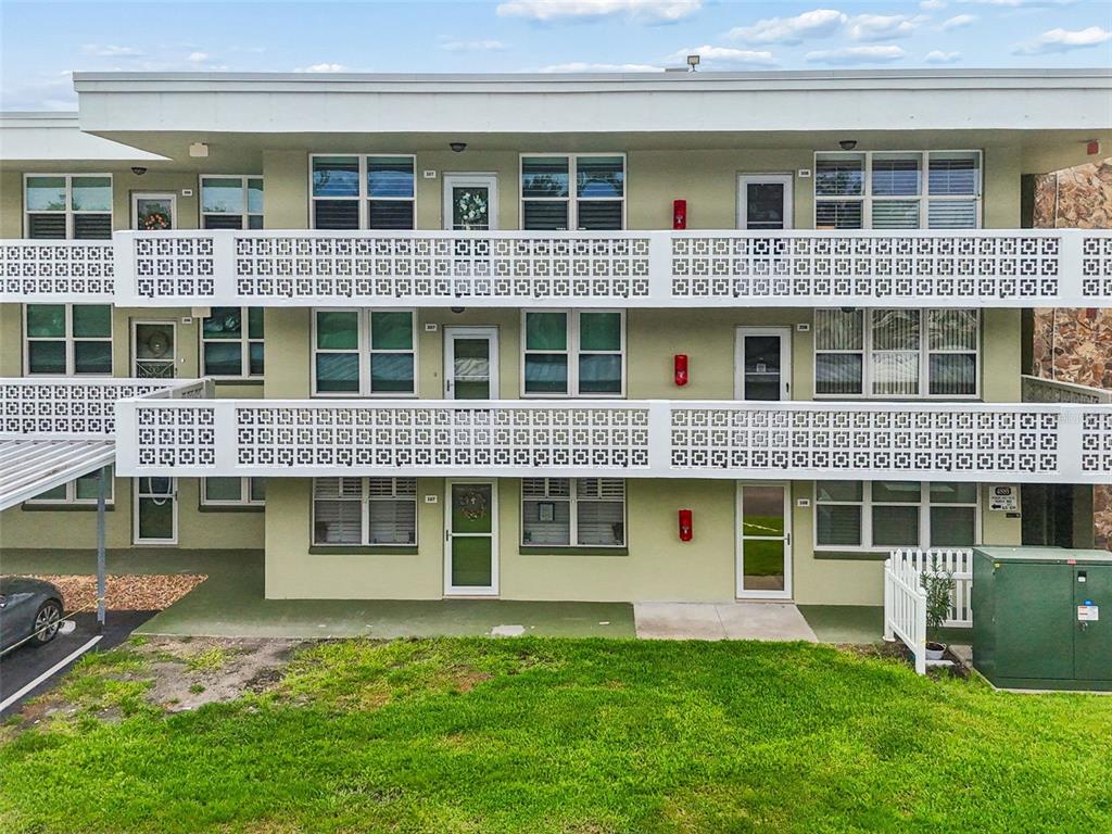 A three-story apartment building features light green stucco walls, white railings, and multiple windows — 4885 1ST ST NE UNIT 307, ST PETERSBURG, FL