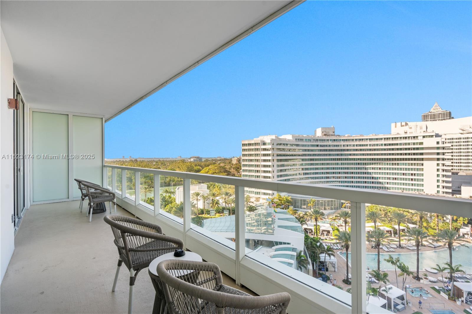 A balcony with outdoor seating overlooks a resort pool area and a large hotel building — 4391 COLLINS AV # 1007, Miami Beach FL 33140, MIAMI BEACH, FL