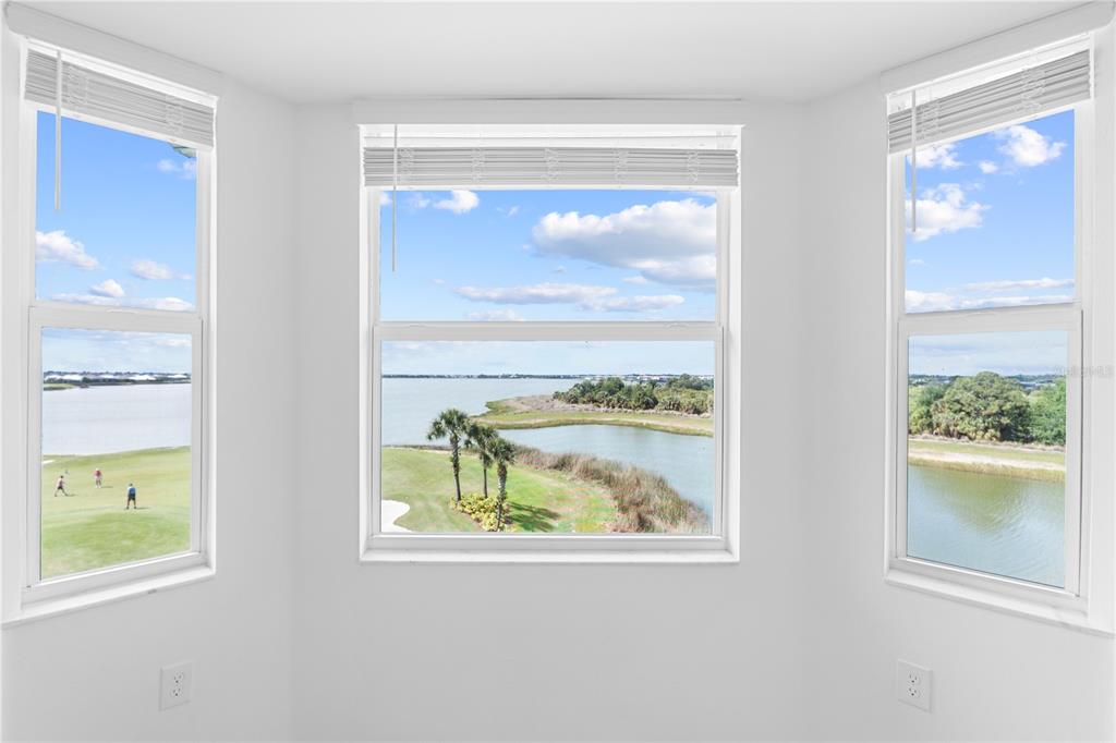 A bright room with three windows overlooking a golf course and a lake — 43000 GREENWAY BOULEVARD UNIT 145, PUNTA GORDA, FL