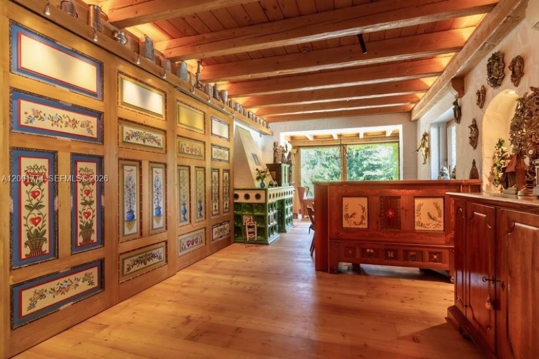 A rustic room features wood-paneled walls with folk art paintings, exposed ceiling beams, and hardwood floors — 5 Via Giuseppe Verdi, Fusine in Valromana, Tarvisio, FL