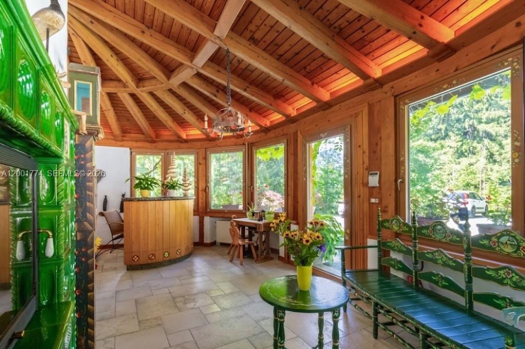 A sunroom features a wooden vaulted ceiling, tile flooring, a green tiled stove, and windows — 5 Via Giuseppe Verdi, Fusine in Valromana, Tarvisio, FL
