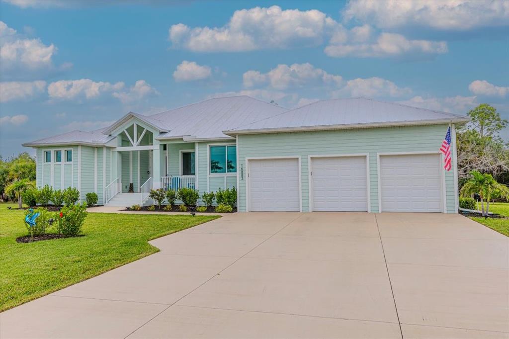 A light green single-story house with a three-car garage and a metal roof — 16883 ACAPULCO ROAD, PUNTA GORDA, FL