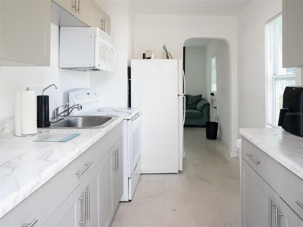 A galley kitchen features gray cabinets, white appliances, and marble-look countertops — 3227 5TH AVE S, ST PETERSBURG, FL