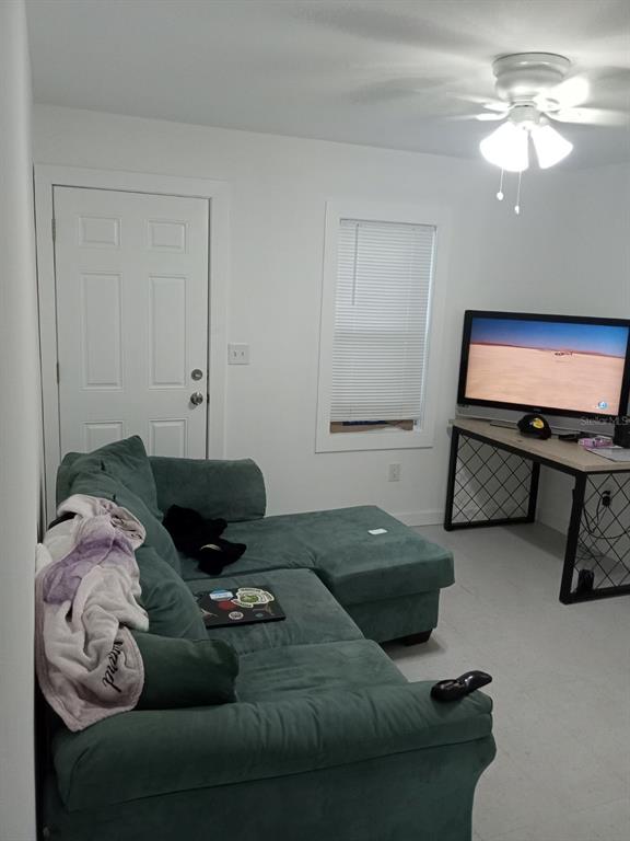 A living room features a green sectional sofa, a television on a desk, and a ceiling fan — 3227 5TH AVE S, ST PETERSBURG, FL